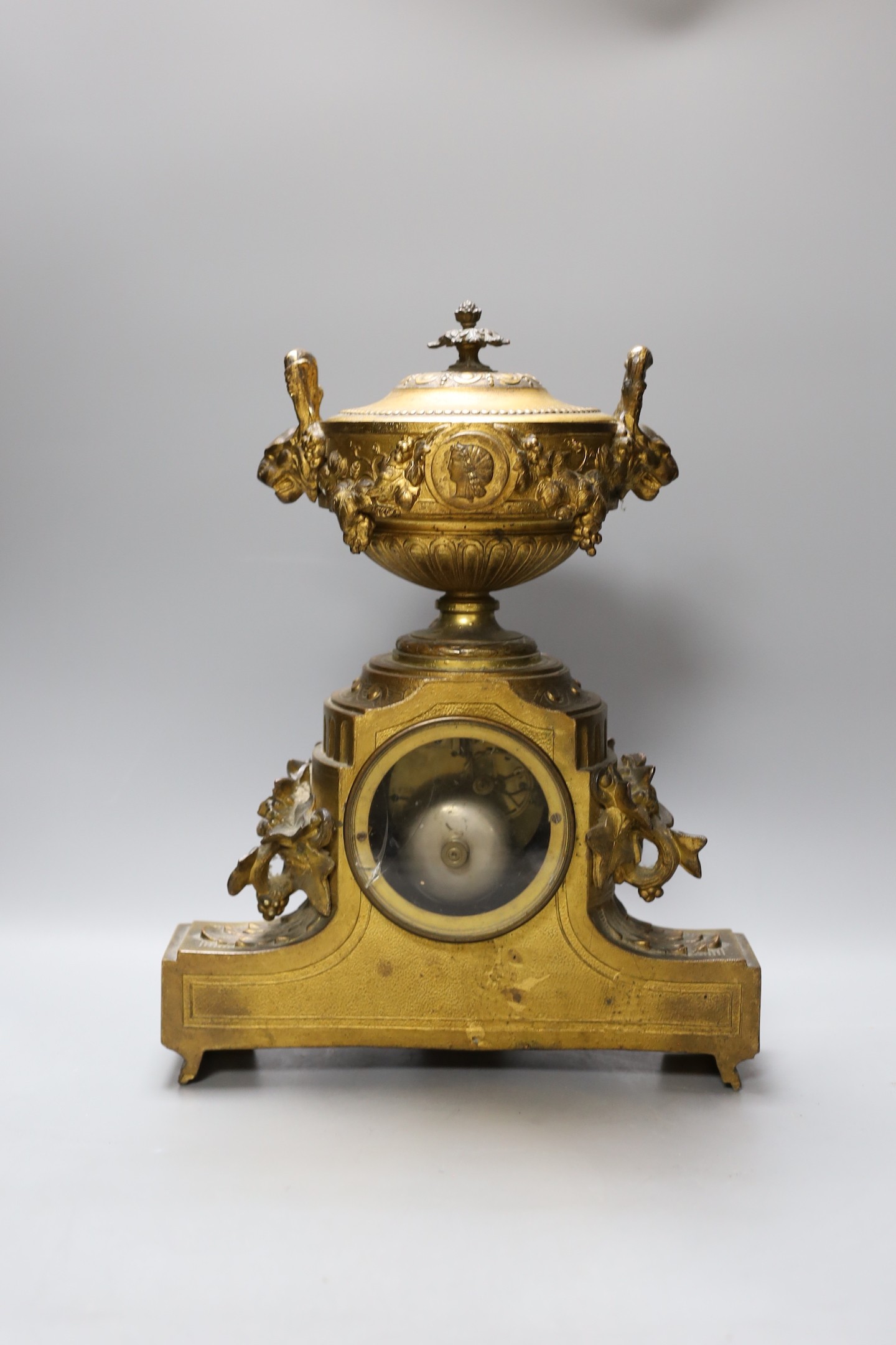 A French gilt metal mantel clock, designed with ornate vines and an urn, 38 cms high